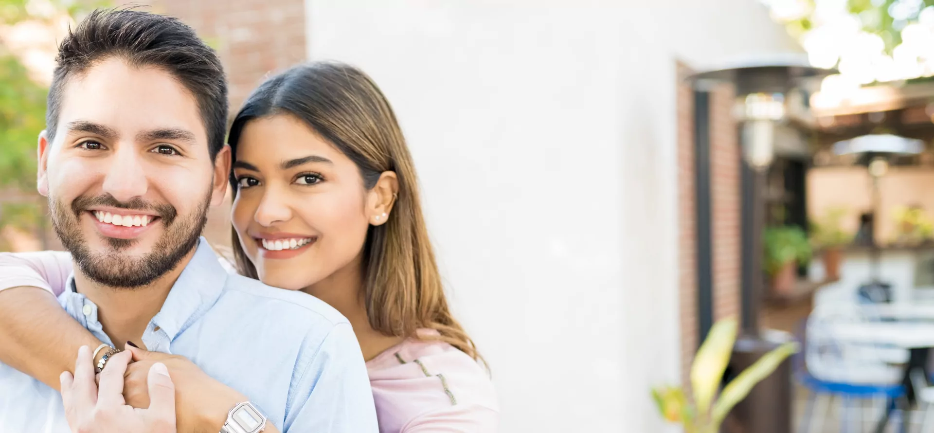A smiling couple embracing outdoors on a sunny patio