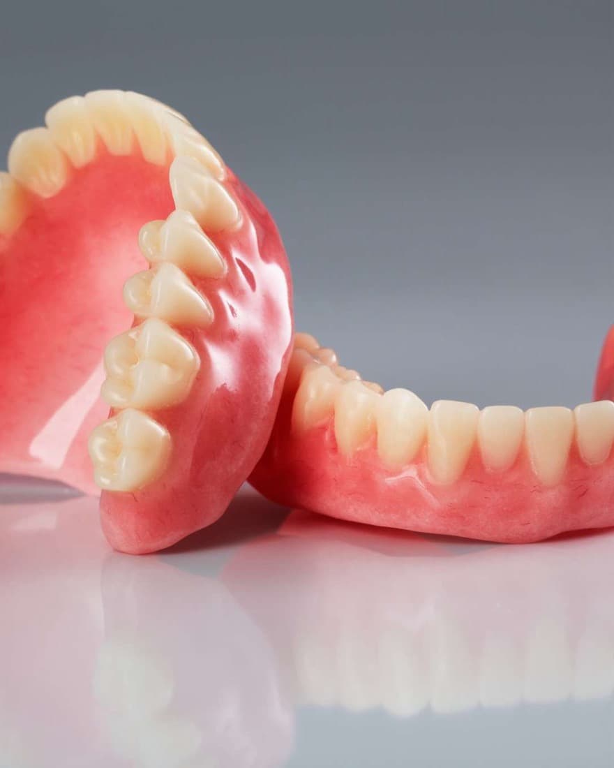 A full set of upper and lower dentures resting on a grey surface