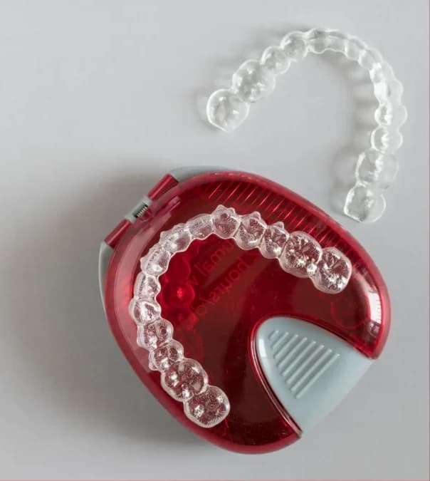 A clear Invisalign aligner resting in its red case
