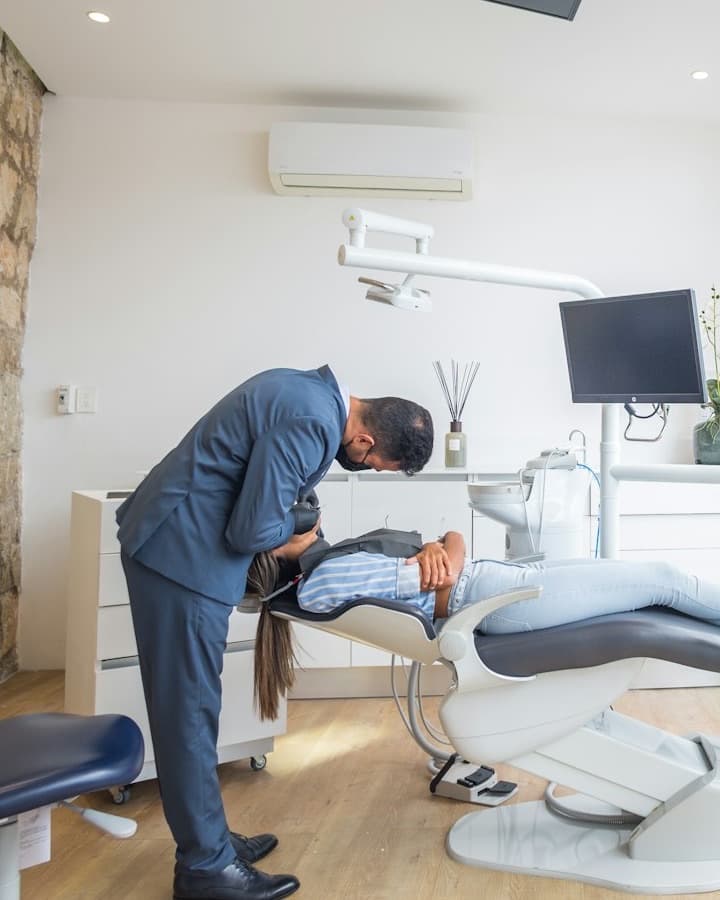 A dentist leaning over a patient in a bright, modern treatment room