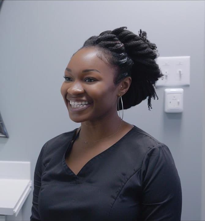 A smiling team member in black scrubs in the treatment room